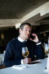 Handsome businessman dressed in the suit drinking wine. Businessman talking to the phone.
