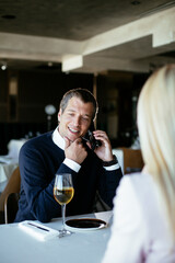 Handsome businessman dressed in the suit drinking wine. Businessman talking to the phone.