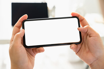 Closeup of young woman hand holding smartphone on the table and the screen is blank, social network concept.
