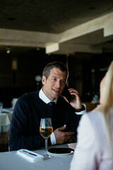 Handsome businessman dressed in the suit drinking wine. Businessman talking to the phone.