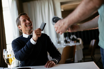 Businessman paying the bill with a credit card in restaurant