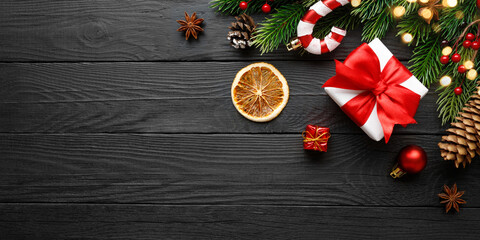 Christmas decoration with fir and gift on a black wooden background