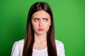 Fototapeta premium Photo portrait of frowning sad girl looking to side isolated on vivid green colored background