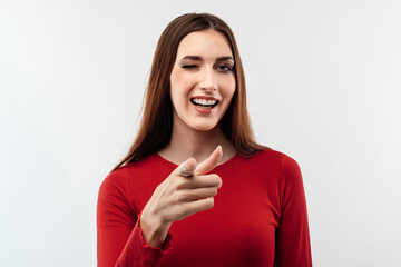 Smiling Young woman with long chestnut hair looking at the camera and pointing her finger at you. Human emotions concept