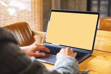 Mockup image of a businesswoman using and typing on laptop computer keyboard with blank white desktop screen on wooden table