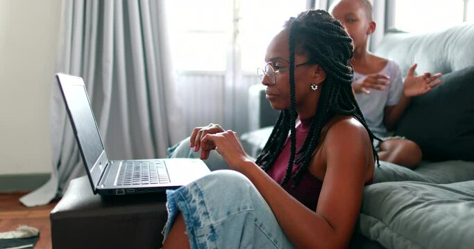 Black mother working from home in front of laptop computer