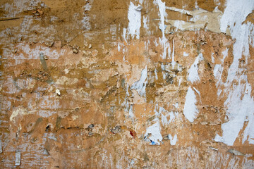 old shabby yellow concrete wall with remnants of paper ads. rough surface texture