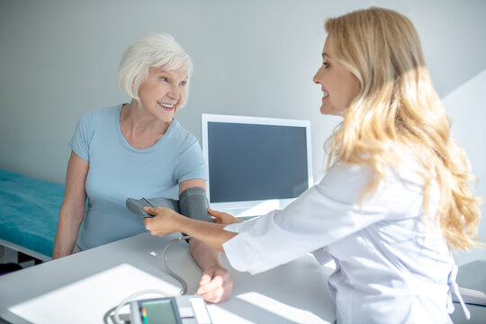 Cardiologist measuring blood-pressure to good-looking elderly woman