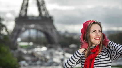 Fototapeta na wymiar Young stylish woman in red beret and autumn clothing oudoors with Eiffel tower