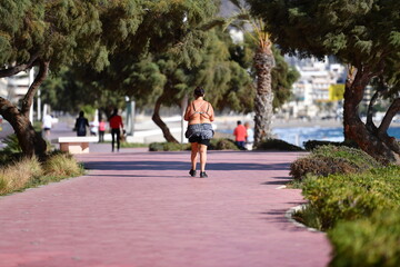 Obraz premium An overweight shirtless woman plays sports on a beach promenade in Benidorm-Spain.