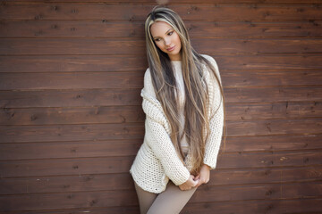 Beautiful woman posing in a warm knitted sweater on a sunny day in the street.