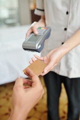 Hotel maid with payment terminal taking credit card and accepting payment for room service