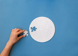Hand putting piece in round puzzle - obrazy, fototapety, plakaty