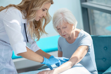 Obraz premium Long-haired smiling nurse making injection to an elderly woman