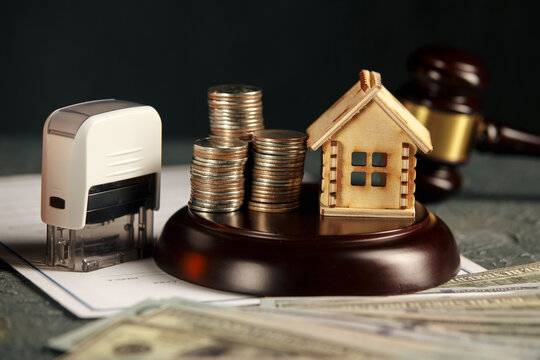 A row of coins on a small house model and a law auction hammer.