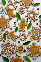Christmas ginger cookies, snowflake shape, icing cream with pomegranate and green leaves. Top view. Abstract Christmas food.