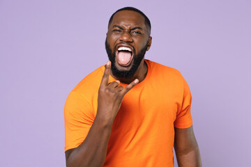 Crazy screaming young african american man wearing basic casual orange t-shirt standing depicting...