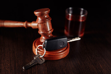 Car key, wooden judge gavel and whiskey alcohol drink in a glass. Drink driving is punishable.