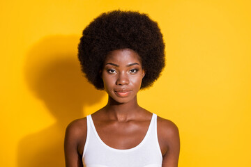 Fototapeta na wymiar Photo of charming black girl serious look camera big volume hairstyle wear white singlet isolated yellow color background