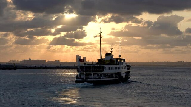 Ferry (aka vapur) with passengers, leaving Kadikoy at sunset time, Istanbul, Turkey