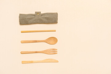 Set of Eco friendly bamboo cutlery on camel color background. Plastic free concept. Close-up, top view.