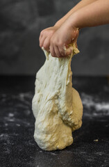 children's hands work with dough on the kitchen table sprinkled with flour