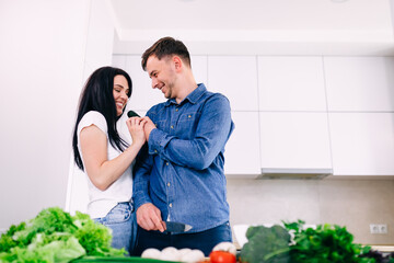 Young happy couple are enjoying and preparing healthy food in their kitchen.