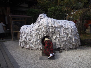 An Asian woman in a traditional Japanese kimono walks through a hole in a monument to break a bad relationship and make a good one, Yasui Konpira-gu Shrine, Kyoto, Japan