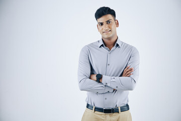 Portrait of confident young Indian entrepreneur crossing arms and smiling at camera