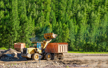 Bulldozer and dump truck work on the construction
