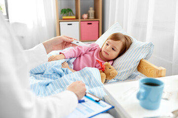 healthcare, medicine and people concept - close up of doctor with thermometer measuring temperature of little sick girl lying in bed at home