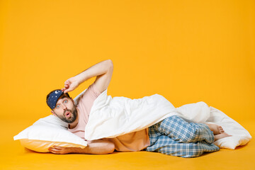 Full length shocked amazed young bearded man in pajamas home wear sleep mask lying with pillow...