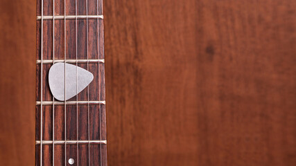 guitar pick on wooden guitar neck on the frets of the guitar on wooden background