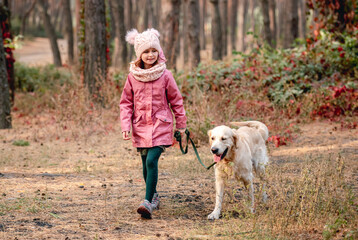 Little girl walking with dog in pine wood