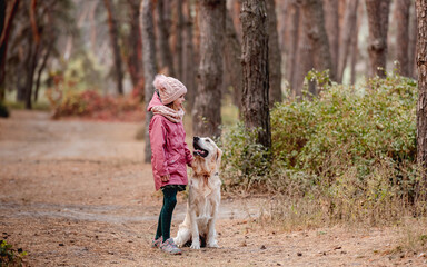Little girl walking with dog in pine wood