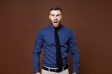 Shocked worried irritated bearded young business man wearing blue shirt tie keeping mouth open swearing isolated on brown colour background studio portrait. Achievement career wealth business concept.
