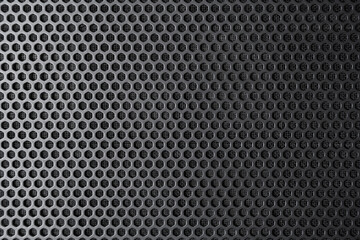 Industrial background. Black metal surface with regular round holes as texture (abstract)