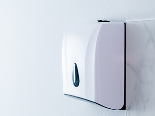 White plastic tissue paper box hanging on white wall in the bathroom. Paper towel dispenser. Close-up