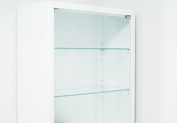 White new empty cabinet with thin glass shelves. Minimalistic light cupboard. Medical room. Close-up