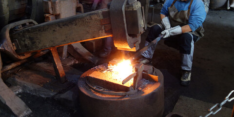 Dicker schwerer Schmiedehammer hämmert auf glühenden Stahl. Altertümliche Industrieanlage....
