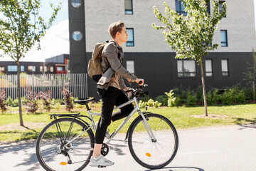 lifestyle, transport and people concept - young man or teenage student boy with backpack riding...