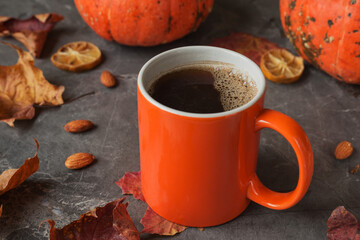 Autumn composition of mug of coffee, pumpkins, maple leaves, almond on dark stone table. Fall time, home comfort.