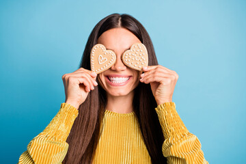 Photo portrait of woman covering two eyes with heart-shaped gingerbread cookies isolated on pastel...