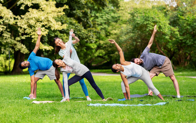 fitness, sport and healthy lifestyle concept - group of happy people doing yoga with coach at summer park