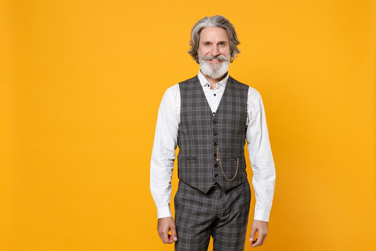 Smiling elderly gray-haired mustache bearded business man in checkered suit waistcoat white shirt stand looking camera isolated on yellow background studio portrait. Achievement career wealth concept.