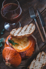 Baked stuffed pumpkin with meat and cheese. White bread toast and a glass of beer. Rustic food 