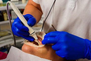 At the dentist's appointment, tartar removal, use of ultrasound, patient and dentist. Retractor for isolation of lips and gums.