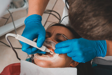 At the dentist's appointment, tartar removal, use of ultrasound, patient and dentist. Retractor for isolation of lips and gums.