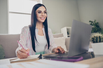 Photo of young cheerful girl hold pen write notepad hand keyboard wear spectacles shirt in home workstation indoors