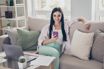 Photo of young business lady sit sofa look screen smartphone relax wear eyeglasses shirt in home...